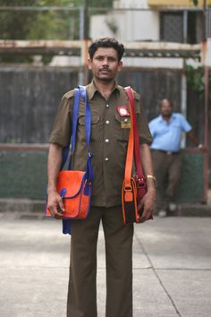 a man in uniform holding two orange and blue bags