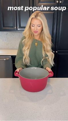 a woman is holding a large pot in her hands and the words most popular soup on it