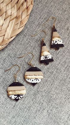 three earrings with black and white designs hanging from it's earwires next to a basket