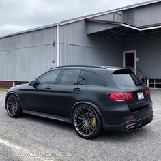 a black mercedes benz wagon parked in front of a large building with its door open