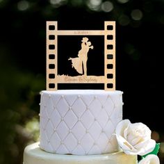 a white wedding cake with a film strip design and a silhouette of a woman on top