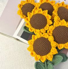 there are crocheted sunflowers on top of a book and some papers