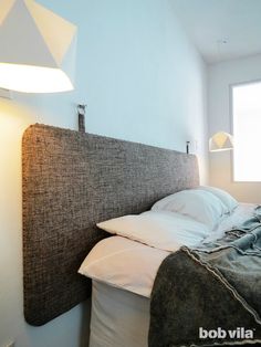 a bed with pillows and blankets on top of it next to a lamp in a room