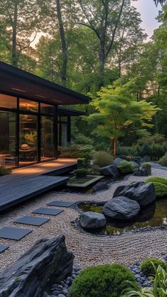 a japanese garden with rocks and plants in the foreground is lit up at night