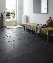 a room with black tile flooring and two benches in front of the door that leads to an outside patio