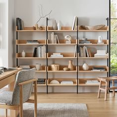 a living room filled with furniture and bookshelves next to a wooden table in front of a window