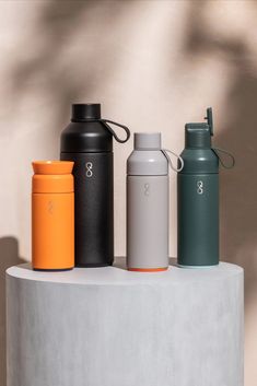 three different colored water bottles sitting on top of a cement structure