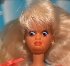 a close up of a doll with blonde hair and blue eyes