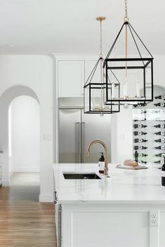 a white kitchen with an island and wine rack hanging from the ceiling over the sink