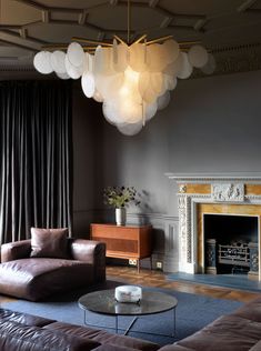 a living room filled with furniture and a fire place under a chandelier hanging from the ceiling