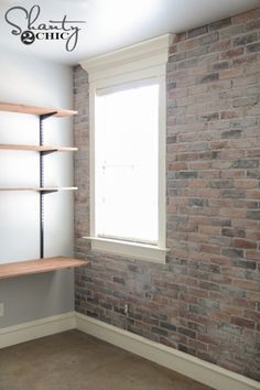 an empty room with brick walls and shelving unit in the corner, next to a window