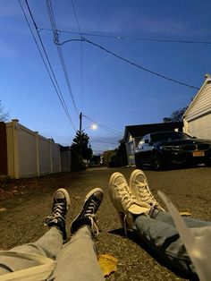 two people sitting on the ground with their feet up in the air and one person wearing sneakers