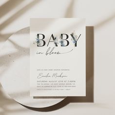 a baby is in bloom card next to a paper plate on a white tablecloth