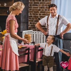 a man and woman standing next to a little boy in front of a table with a cake on it