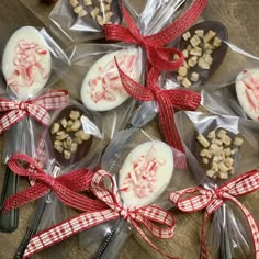 several spoons with candy on them are wrapped in cellophane and tied with red ribbon