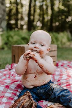 a baby sitting on top of a red and white checkered table cloth eating food