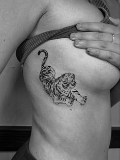 a black and white photo of a tiger tattoo on the side of a woman's stomach