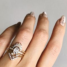 a woman's hand with two rings on her fingers and an engagement ring in the middle