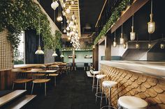 the interior of a restaurant with wooden tables and stools, plants growing on the wall