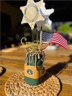 an american flag and sheriff badge on top of a cup with a keychain in the shape of a cowboy's hat