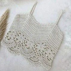 a crocheted bag sitting on top of a white blanket next to a feather