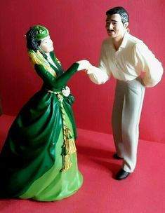 a man and woman figurine standing next to each other on a red surface