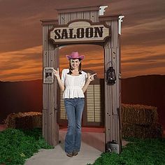 a woman standing in front of a saloon sign with a cowboy hat on her head