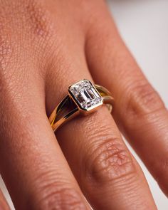 a woman's hand with a diamond ring on top of her finger, showing the center stone