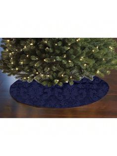 a small christmas tree in a blue vase on a wooden floor with lights around it