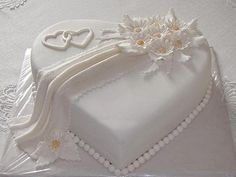 a wedding cake with white frosting and daisies on the top is sitting on a lace tablecloth