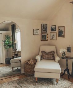 a living room with a white chair and pictures on the wall