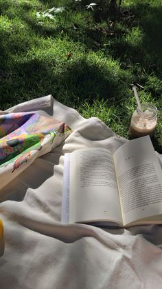 an open book sitting on top of a blanket next to a glass of orange juice