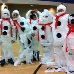 group of children in costumes made to look like snowmen standing on a wooden floor