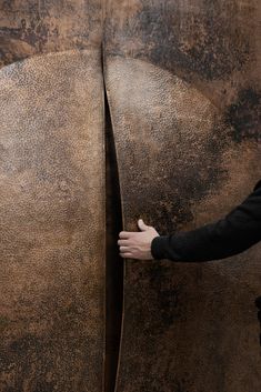 a man standing next to a giant metal object with his hand on it's side