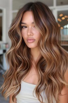 Woman with long, wavy hair and natural makeup, standing indoors. Brown Blonde Caramel Hair, Honey Highlights On Auburn Hair, Hair Colour Caramel Brown, Long Caramel Balayage, Copper Hair Honey Highlights, Bronde Balayage With Copper Tones, Light Chocolate Brown Hair Highlights, Copper Chestnut Hair Color, Skin Color Hair Color Chart