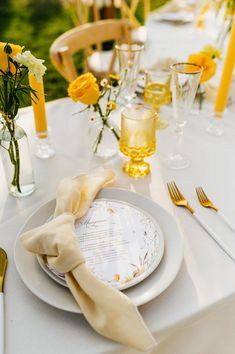 a table set with yellow flowers and plates