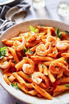 a bowl filled with pasta and shrimp on top of a table