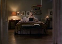 a woman sitting on top of a bed in a bedroom next to a lamp and window