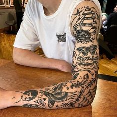 a man sitting at a table with tattoos on his arm