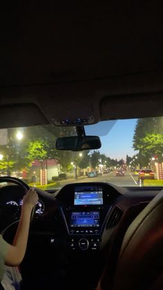 a woman driving a car down a street at night