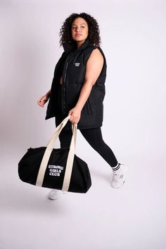 a woman carrying a duffel bag while walking across a white background with her feet in the air