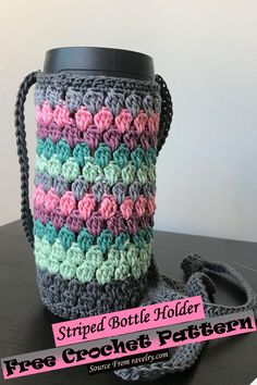 a crocheted coffee cup holder is sitting on a table with a black handle