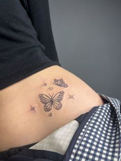 a woman's stomach with butterflies and stars tattoo on her side ribcage