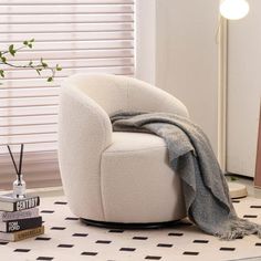 a white chair sitting on top of a floor next to a lamp and a book