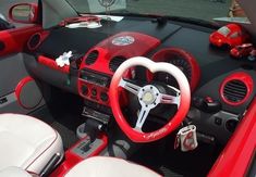 the interior of a red and white car with steering wheel, dash lights, and dashboard