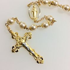 This is a jewelry quality Catholic rosary. Features: Beautiful 8mm Swarovski cream glass pearls. 2" Gold Plated Two-Tone Pewter Crucifix. 1" Gold Plated Two-Tone Pewter Center Piece. Gold base metal bead caps and chain. Packaged in a gold foil gift box. Not finding the rosary you would like? Custom, made to order rosaries are available. I have access to an endless choice of beads, Crucifixes and center pieces. I specialize in special occasion pieces perfect for First Communion, Confirmation, Wed Elegant Rosary With 8mm Beads And Crucifix, Elegant Pearl Beaded Rosary, Elegant Pearl White Pearl Rosary, Elegant Pearl Rosary With Round Beads, Elegant Pearl Rosary With 8mm Beads, Rosary Catholic, Swarovski Pearls, Base Metal, Bead Caps