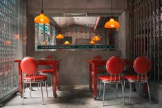 a restaurant with red chairs and yellow lights hanging from the ceiling, along with a mirror on the wall