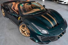 a green sports car parked in a garage with gold rims on it's tires