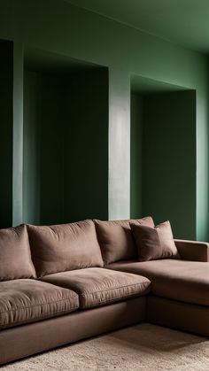 a living room with green walls and a large sectional couch in the middle of it