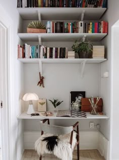 a white desk with books on it and a fur chair in front of the desk